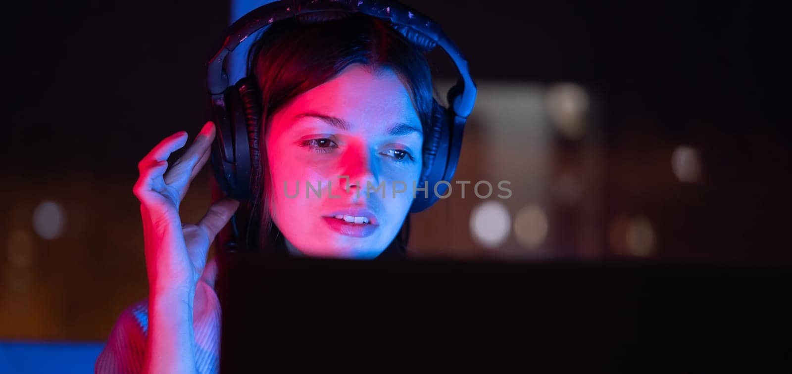 A young girl holds headphones and is listening and composing music, a woman sits with a laptop by the window in her room, works and enjoys the sound.