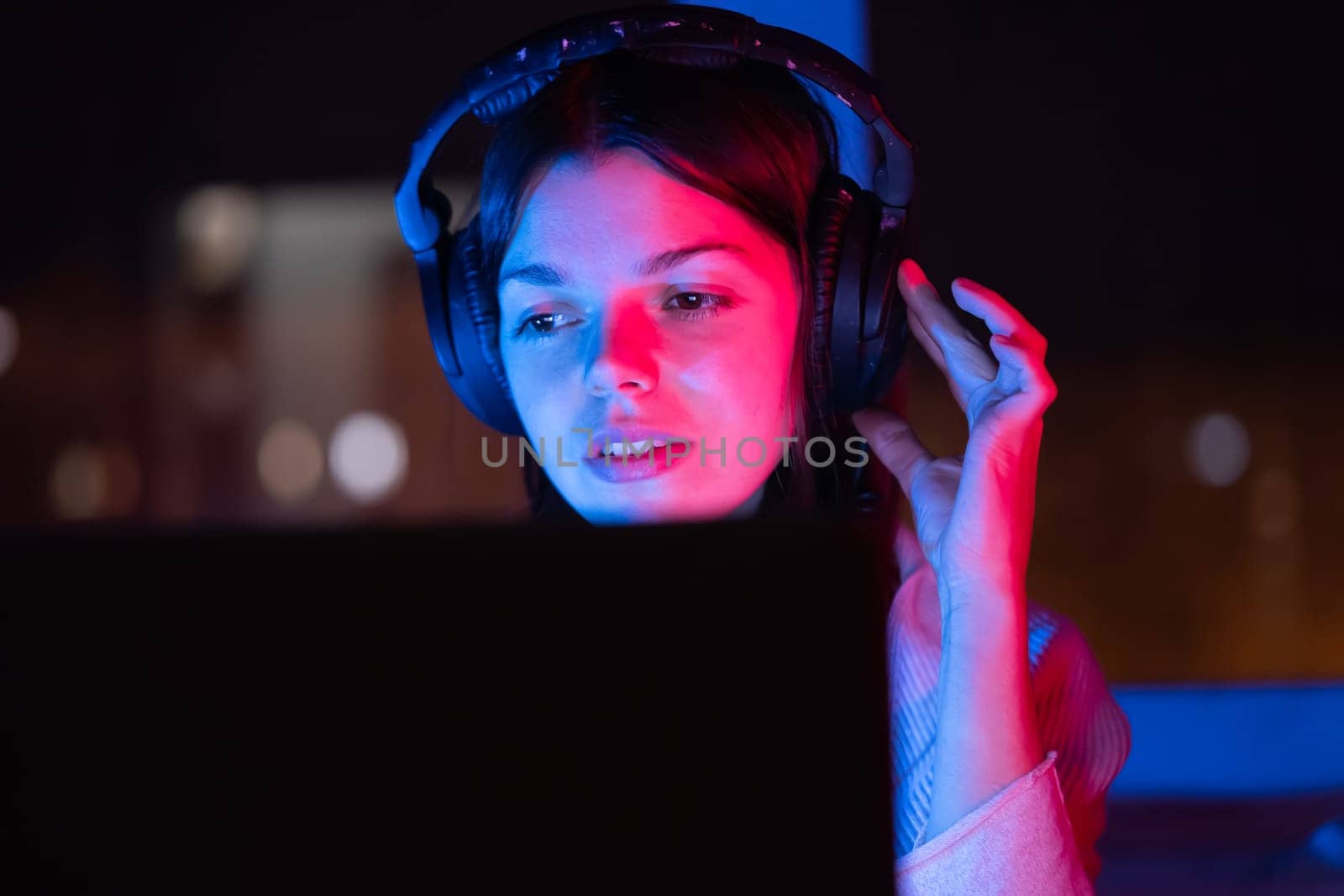 A young girl holds headphones and is listening and composing music, a woman sits with a laptop by the window in her room, works and enjoys the sound.