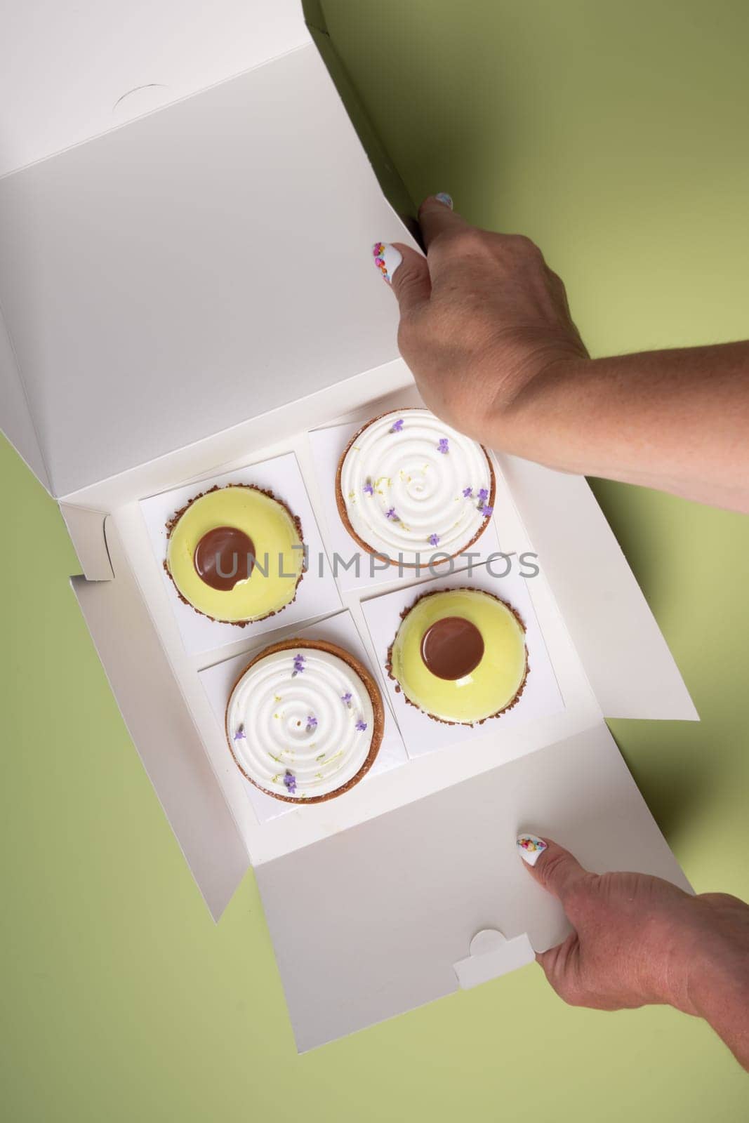 female hands open a box with different cakes dessert home delivery, High quality photo