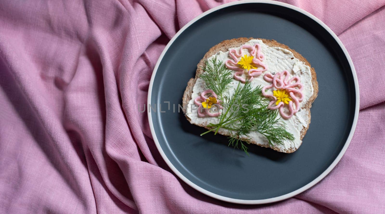 creative sandwich with soft cheese and pink pasta tarama greens, flowers are drawn on the sandwich. High quality photo