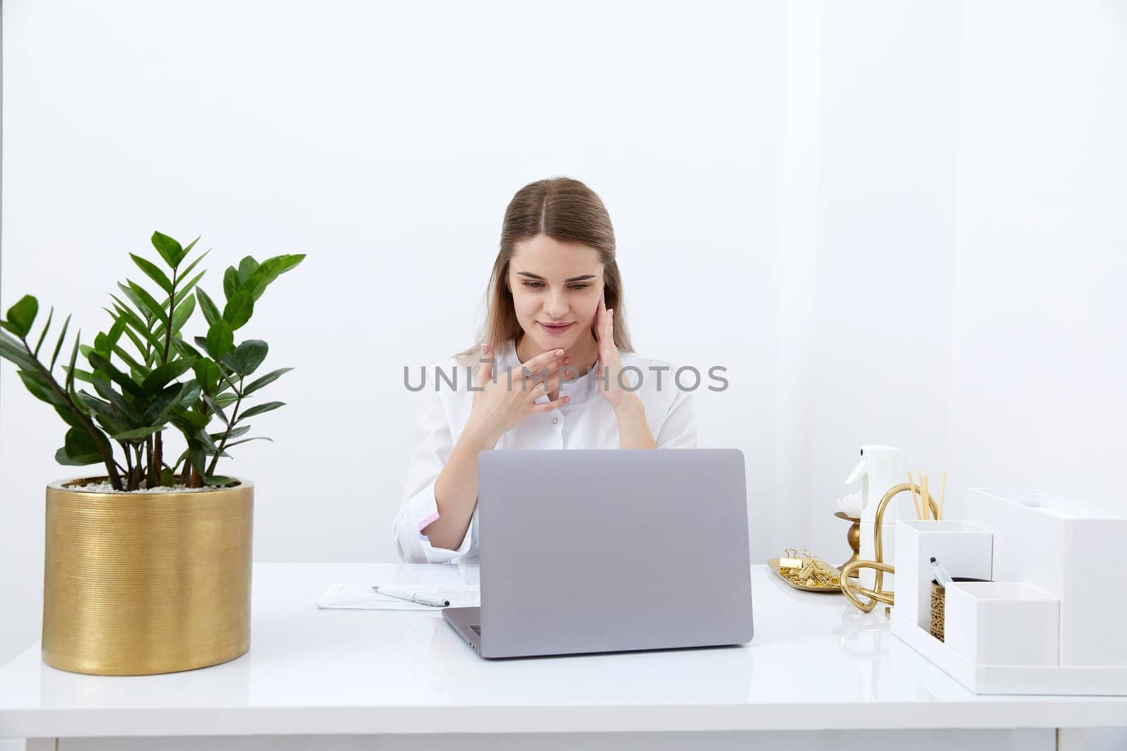 Portrait of female doctor talking to online patient on laptop screen sitting at clinic office desk giving online consultation for domestic health treatment. Telemedicine remote medical appointment