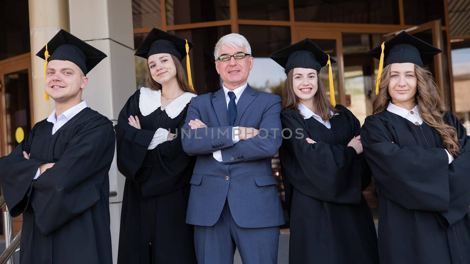 A gray-haired male teacher congratulates students on their graduation from the university