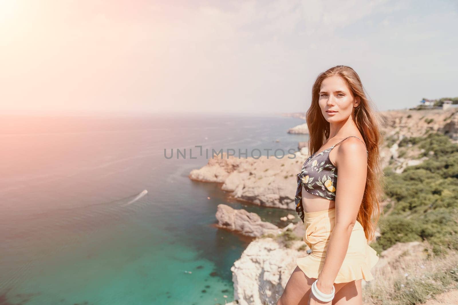 Woman travel sea. Happy tourist taking picture outdoors for memories. Woman traveler looks at the edge of the cliff on the sea bay of mountains, sharing travel adventure journey.