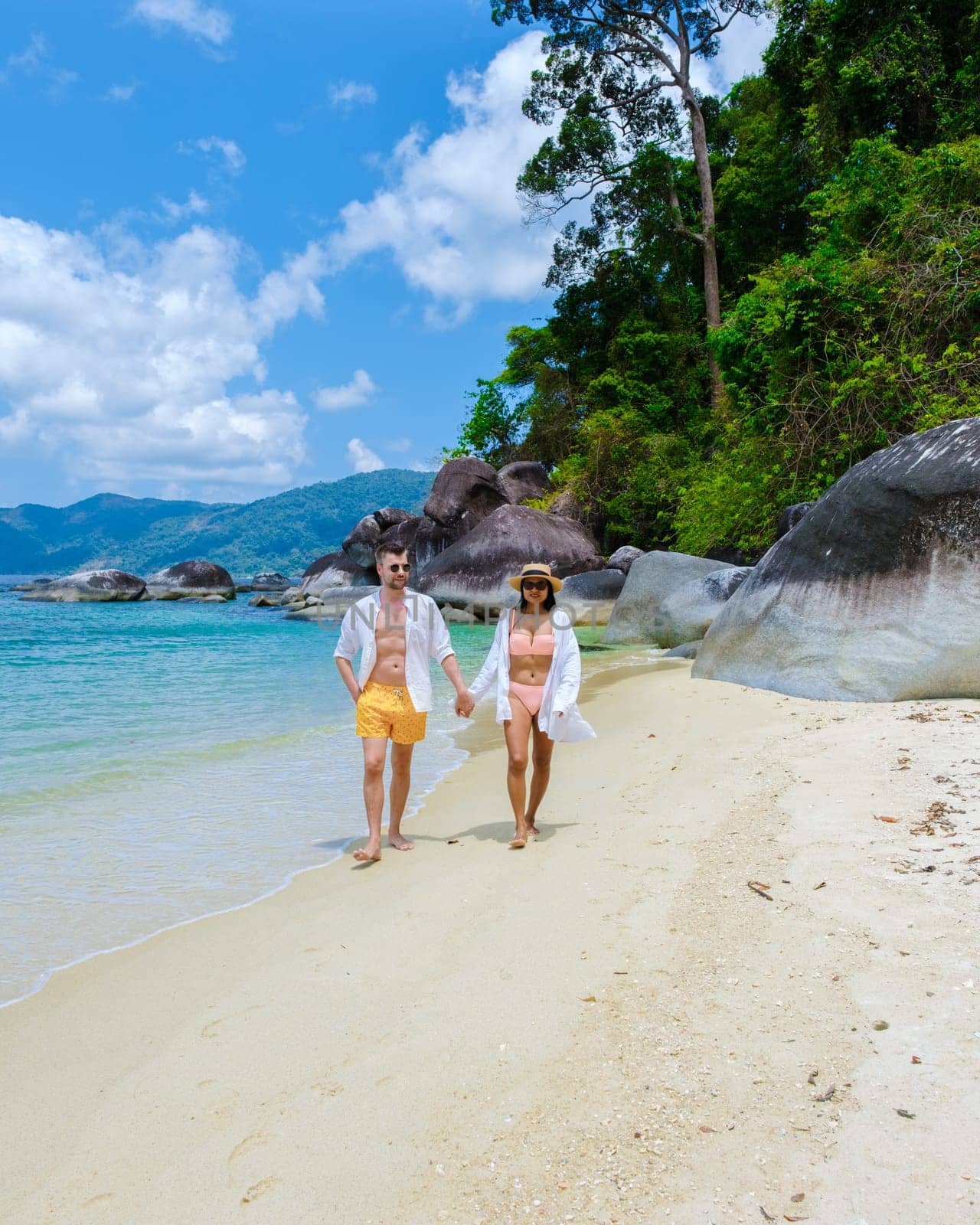 couple of men and women on the beach in swimwear at Koh Adang Island near Koh Lipe Island Southern Thailand with turqouse colored ocean and white sandy beach Tarutao National Park