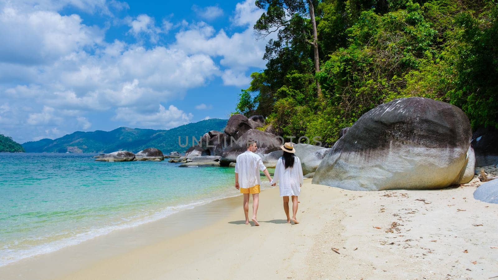 couple on beach in swimwear at Koh Adang Island near Koh Lipe Island Southern Thailand with turqouse colored ocean and white sandy beach Tarutao National Park