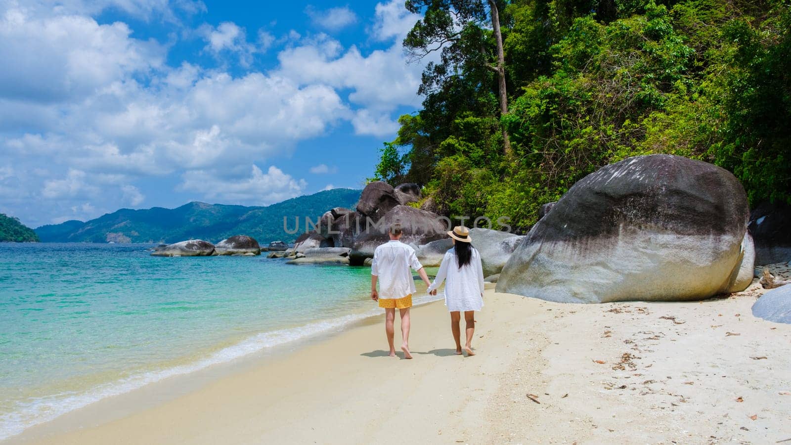 couple of men and women on the beach in swimwear at Koh Adang Island near Koh Lipe Island Southern Thailand with turqouse colored ocean and white sandy beach Tarutao National Park