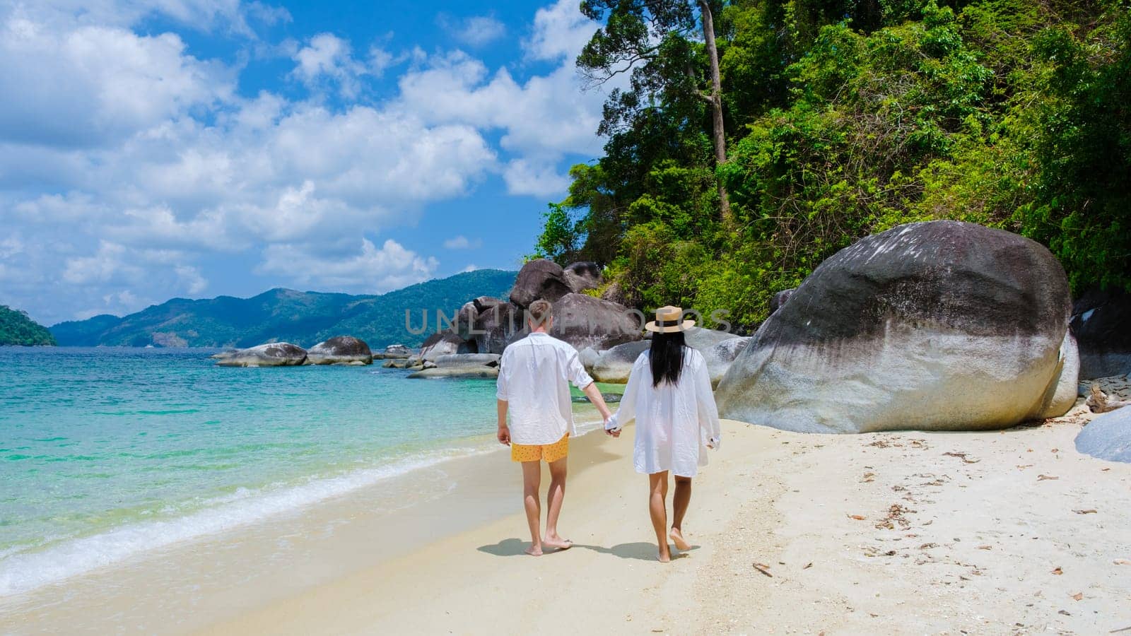 couple of men and women on the beach in swimwear at Koh Adang Island near Koh Lipe Island Southern Thailand with turqouse colored ocean and white sandy beach Tarutao National Park