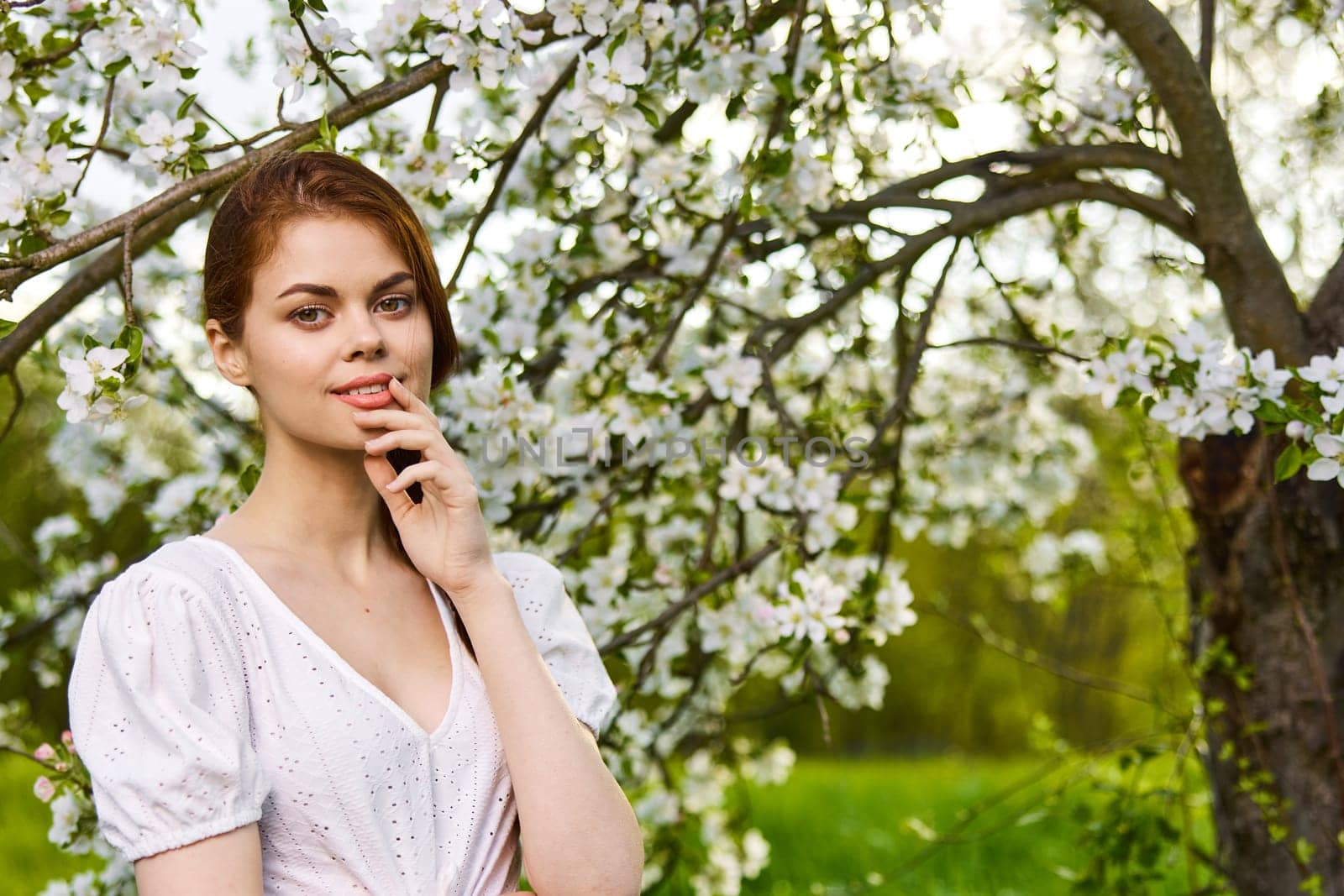 Portrait of happy woman in blooming orchard. Beautiful woman enjoy in nature in spring by Vichizh