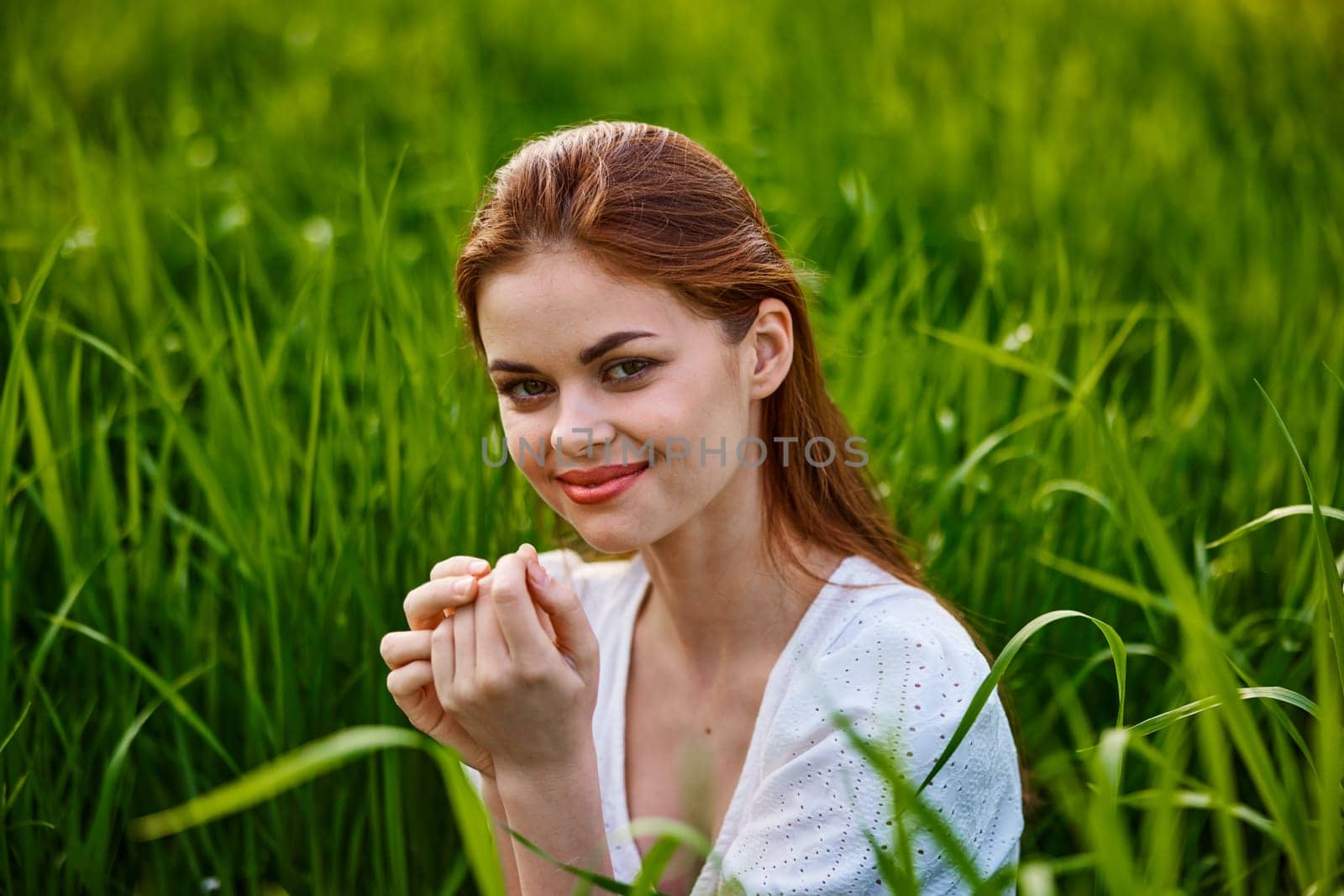 cute, happy woman sitting in tall grass on a sunny day in a light dress. High quality photo