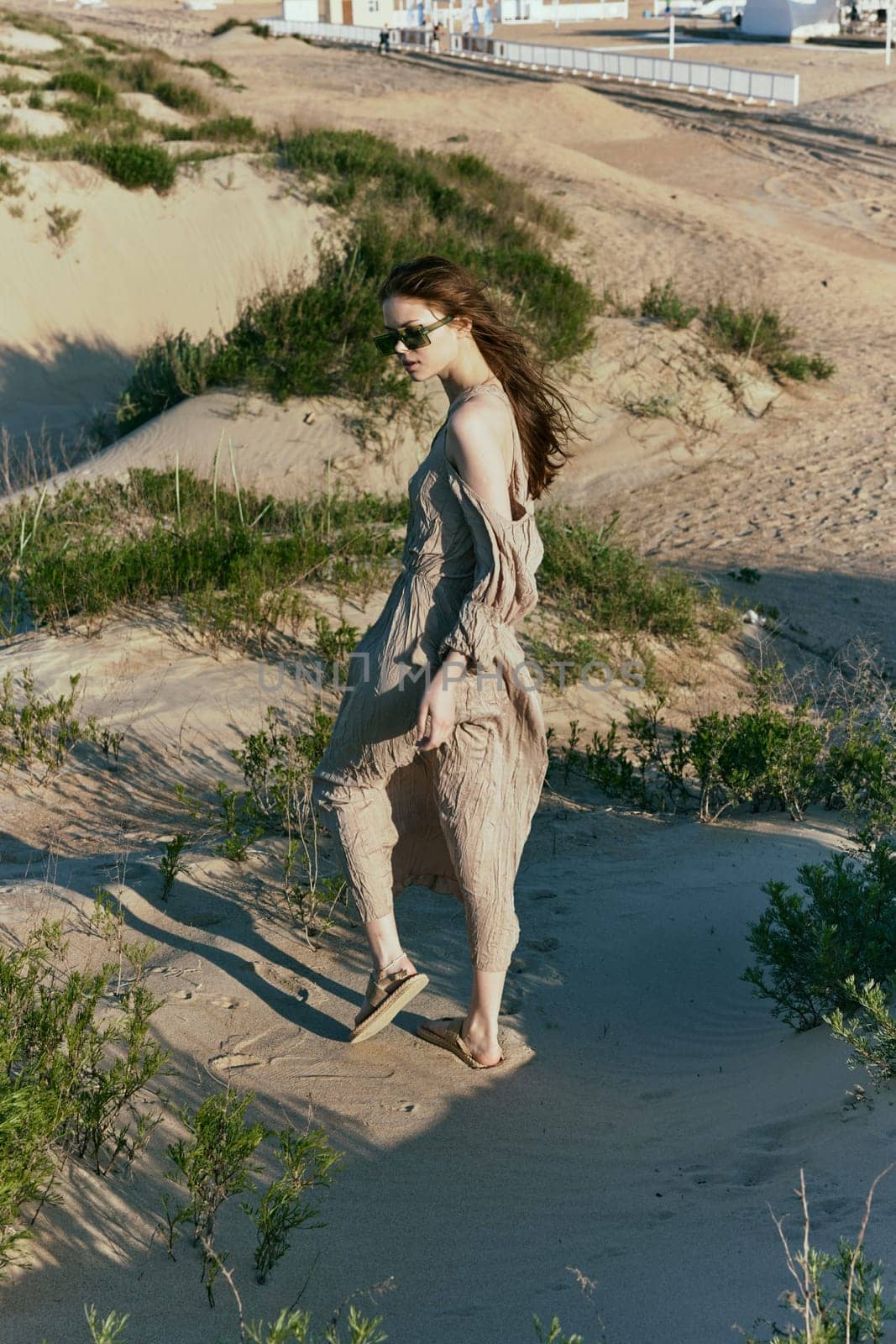 a slender woman in a long dress walks along a wild beach alone. High quality photo