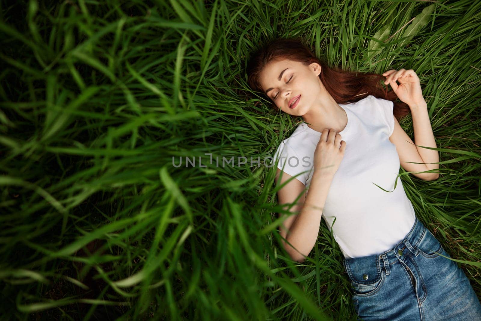 tender, beautiful woman resting lying in the grass in sunny weather by Vichizh