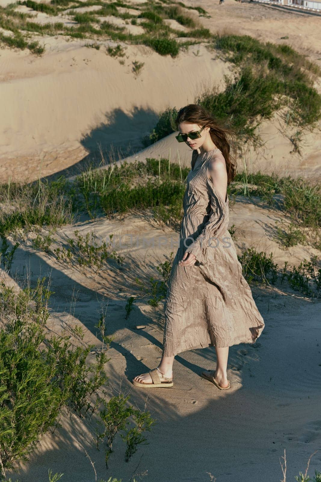 a slender woman in a long dress walks along a wild beach alone by Vichizh