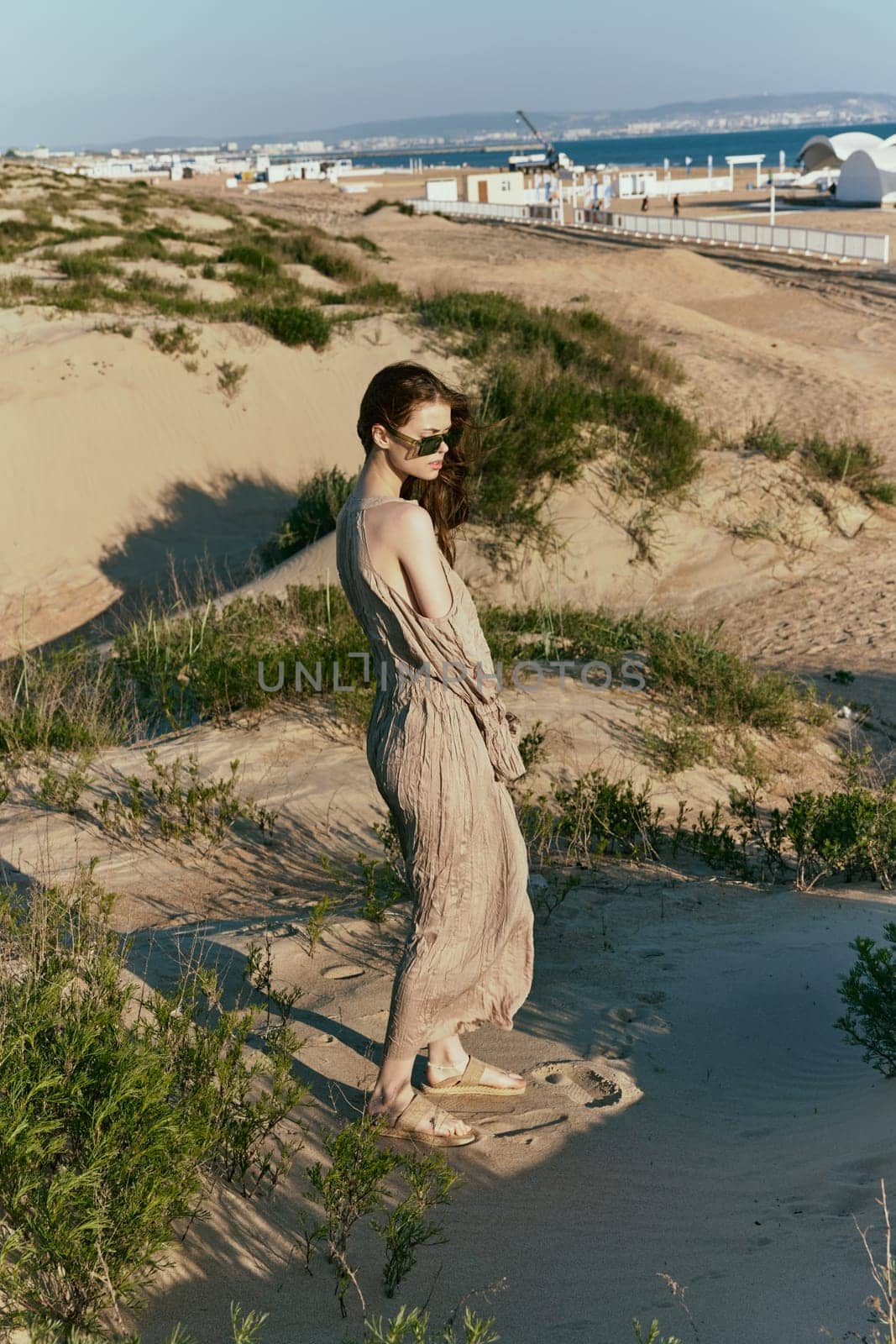 a slender woman in a long dress walks along a wild beach alone. High quality photo