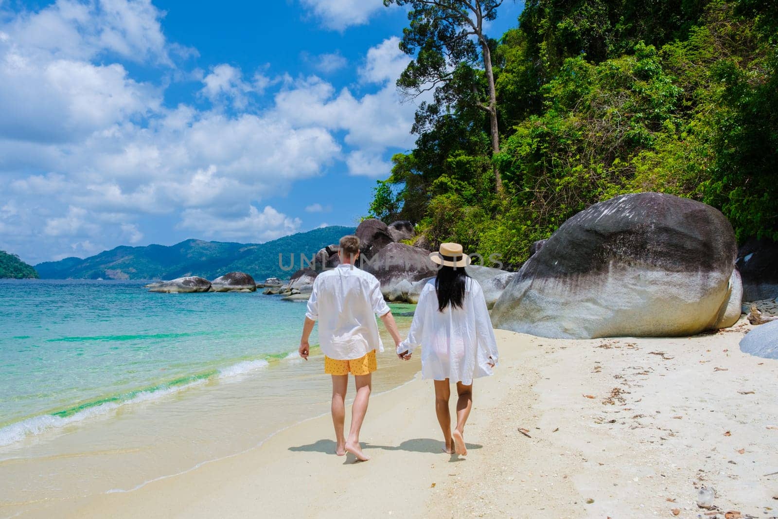 couple of men and women on the beach in swimwear at Koh Adang Island near Koh Lipe Island Southern Thailand with turqouse colored ocean and white sandy beach Tarutao National Park