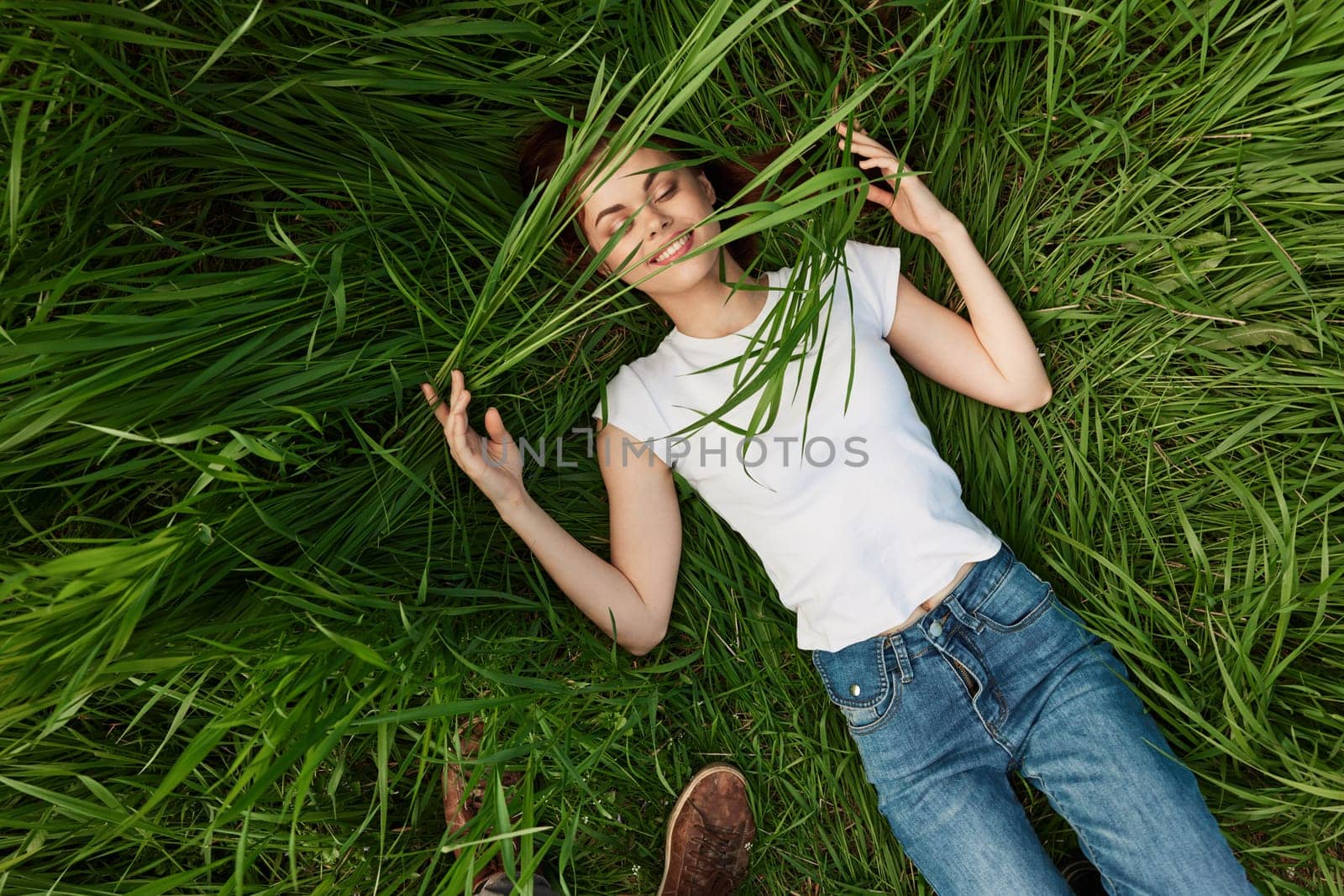 happy woman lying in tall grass biting leaves. High quality photo