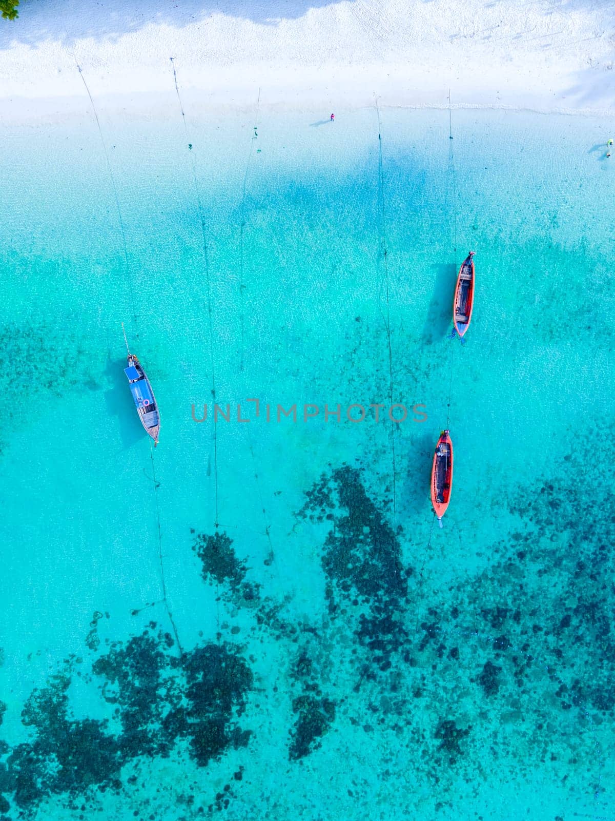 Longtail boats in the blue ocean of Koh Lipe Island Southern Thailand with turqouse colored ocean and white sandy beach at Ko Lipe.