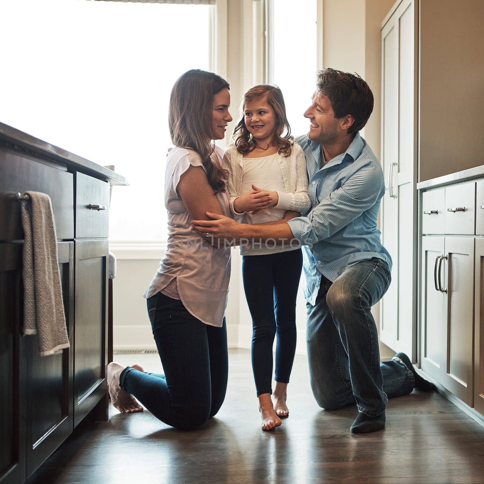 Love makes us a family. two happy parents bonding with their little girl in the kitchen at home