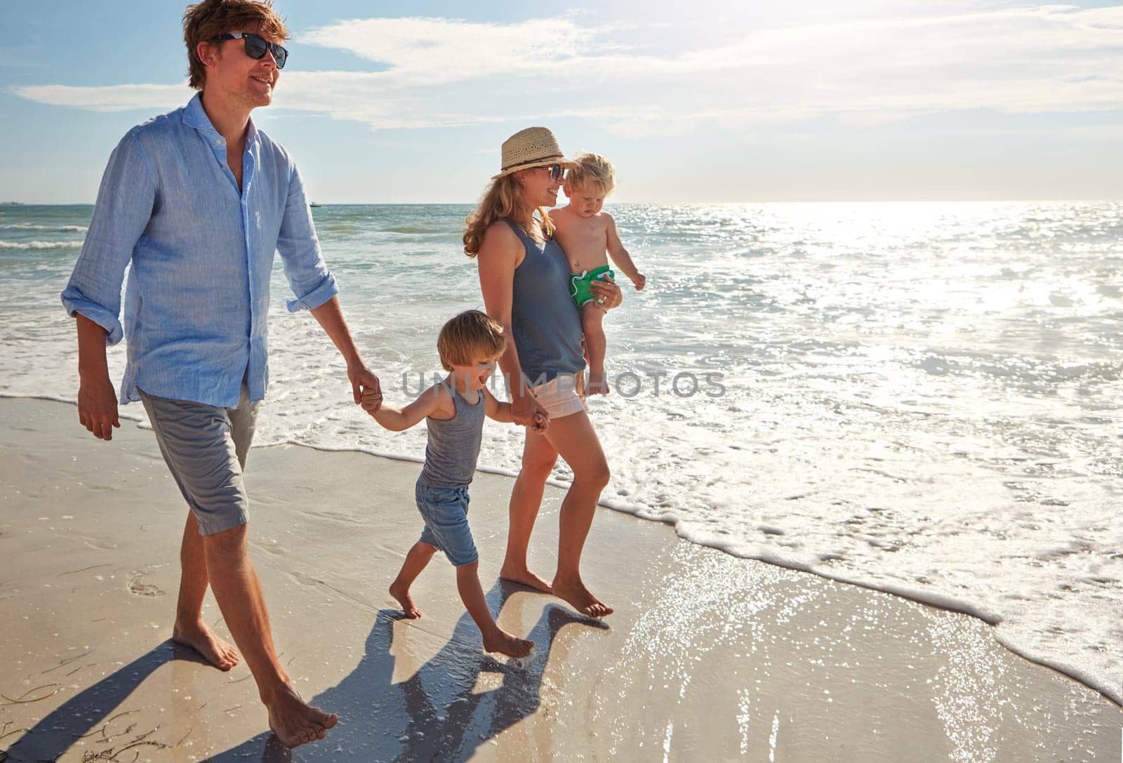 Walking on sunshine. a young family enjoying a summer day out at the beach. by YuriArcurs