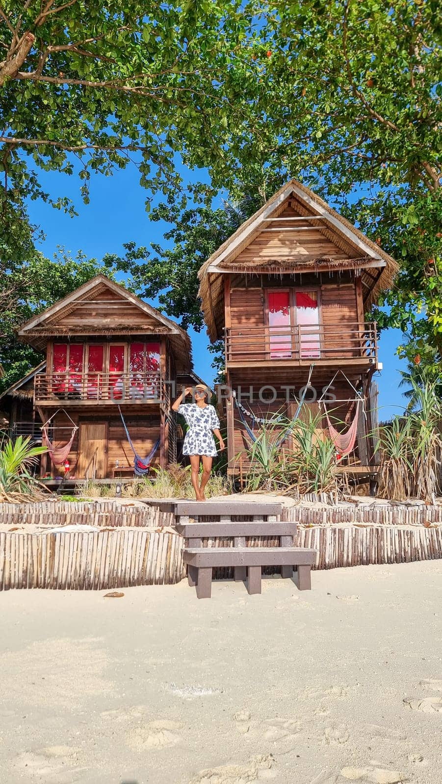 women in front of a bamboo hut bungalows on the beach in Thailand. simple backpacker accommodation in Thailand