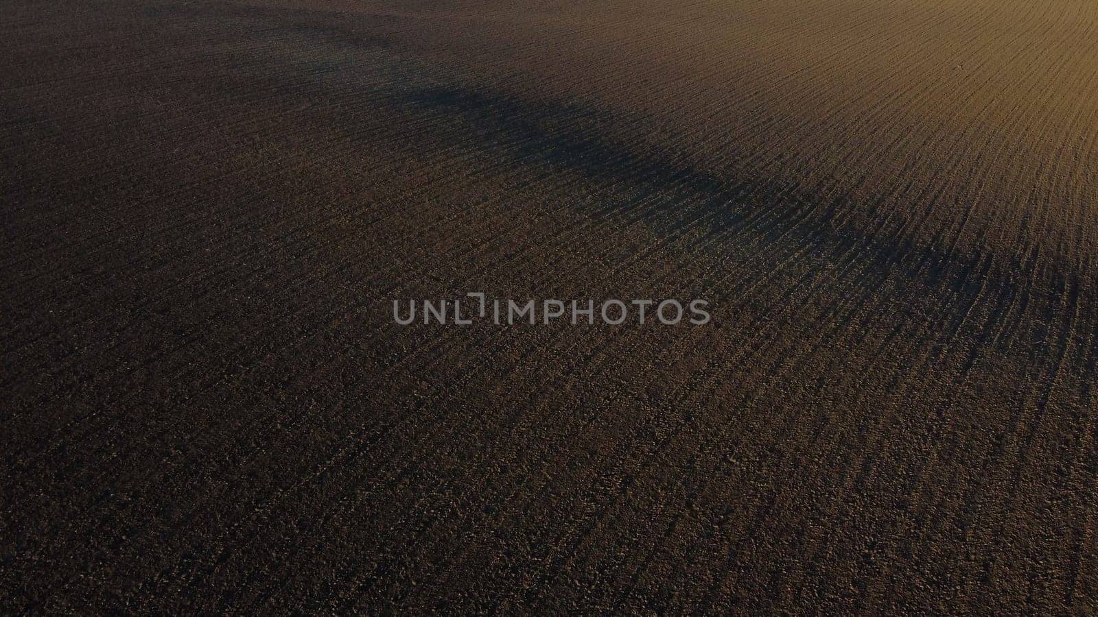 Landscape of plowed up land on an agricultural field on a sunny autumn day. Flying over the plowed earth with black soil. Agrarian background. Black soil. Ground earth dirt priming aerial drone view.