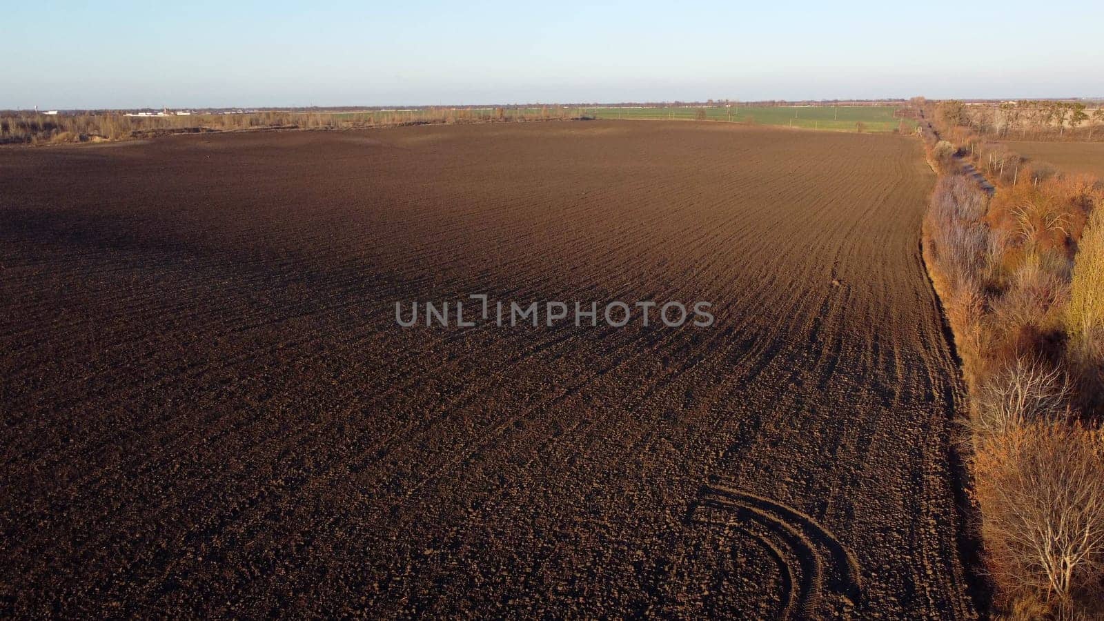 Landscape of plowed up land on an agricultural field on a sunny autumn day. Flying over the plowed earth with black soil. Agrarian background. Black soil. Ground earth dirt priming aerial drone view.