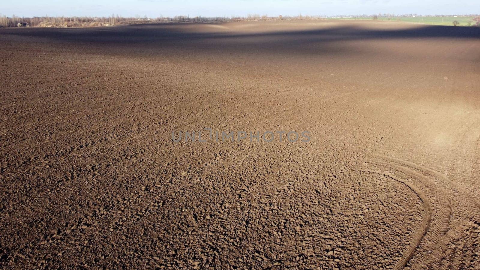 Landscape of plowed up land on agricultural field with cloud shadows on sunny autumn day. Flying over plowed earth with black soil. Agrarian background. Ground earth dirt priming. Aerial drone view.