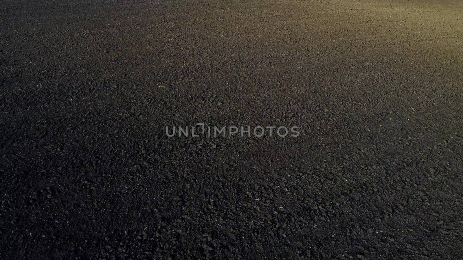 Landscape of plowed up land on agricultural field on sunny autumn day. Flying over plowed earth with black soil. Black soil. Agrarian background. Ground earth dirt priming. Aerial drone view.