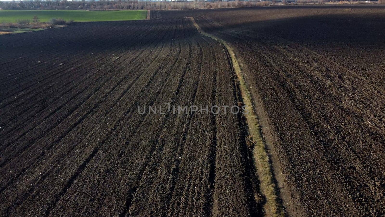 Landscape of plowed up land on agricultural field on sunny autumn day. Flying over plowed earth with black soil. Ground earth dirt priming. Agrarian background. Black soil. Aerial drone view.