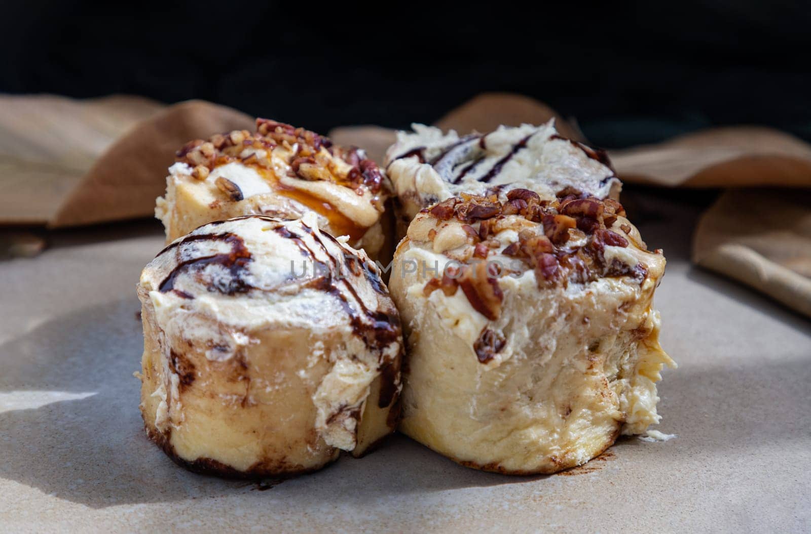 Close up of Two Soft Chocolate Buns topped with rich cream cheese frosting and Two Caramel Pecanbon topped with decadent caramel frosting and pecans on ceramic tray. The concept of delicious food, Selective Focus.