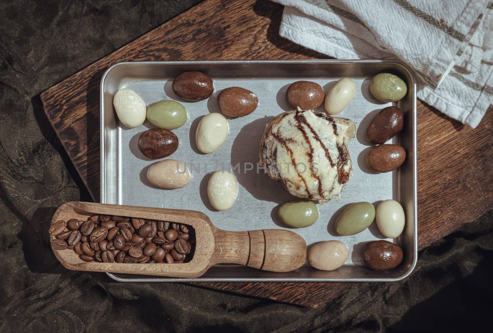 Chocobon (Soft chocolate bun) topped with rich cream cheese frosting and Cinnamon served with assorted almond nuts chocolate in stainless tray with dark background. Top view, Space for text, Selective focus.