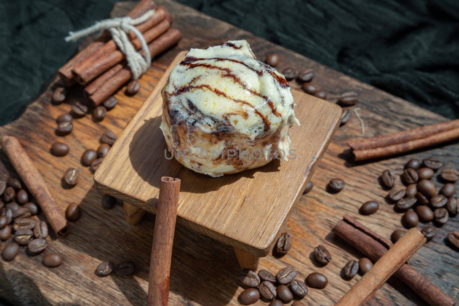 Chocobon (Soft chocolate bun) topped with rich cream cheese frosting and Cinnamon with Coffee beans on wooden with dark background. Selective focus.