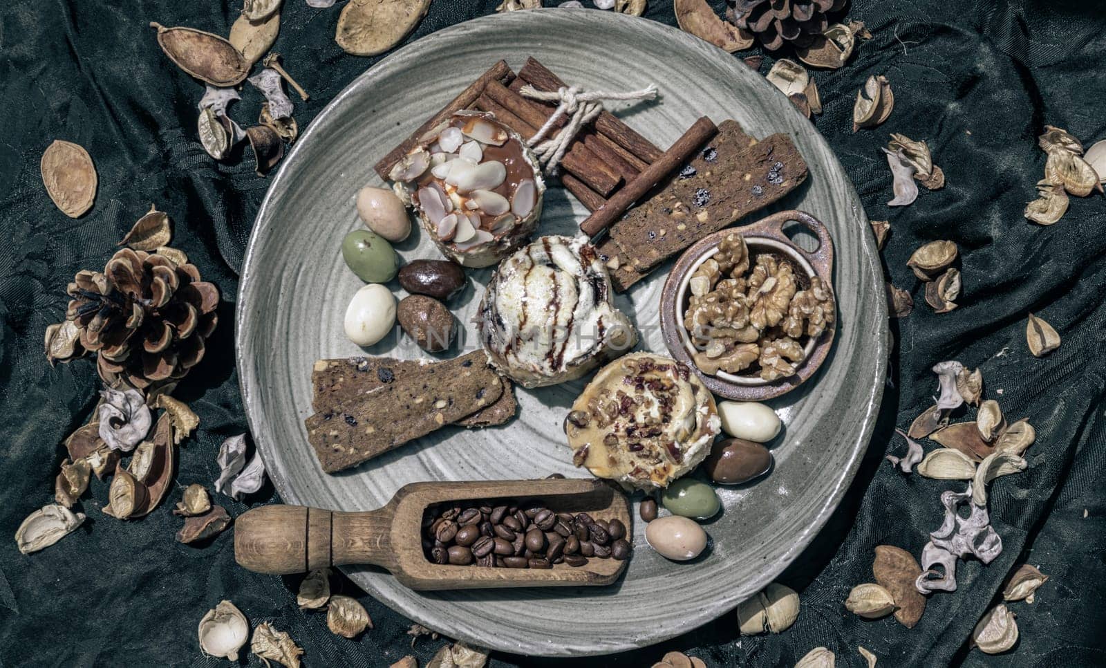 Bakery, Stick cookies, Walnuts, Roasted coffee beans, Colored eggs and Pine cones on Ceramic plate with dark background. Easter desserts, Top view, Selective focus.