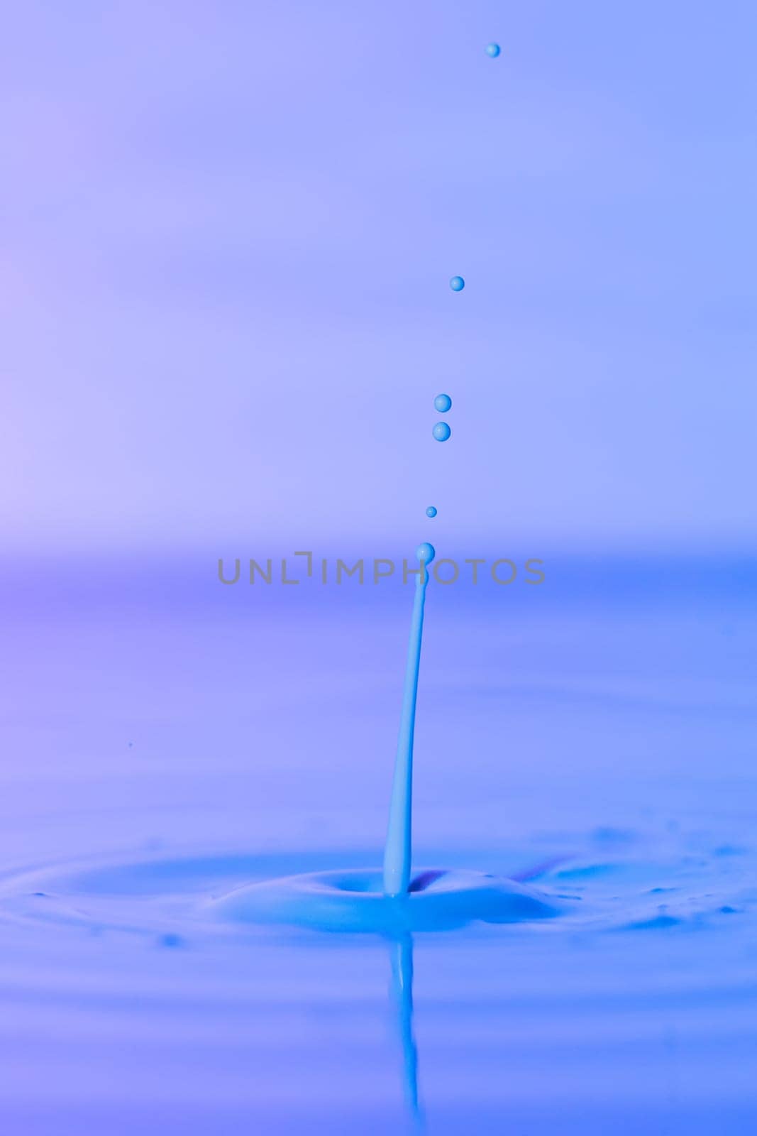 A drop falls into a thick liquid with a blue background. Abstract colorful background