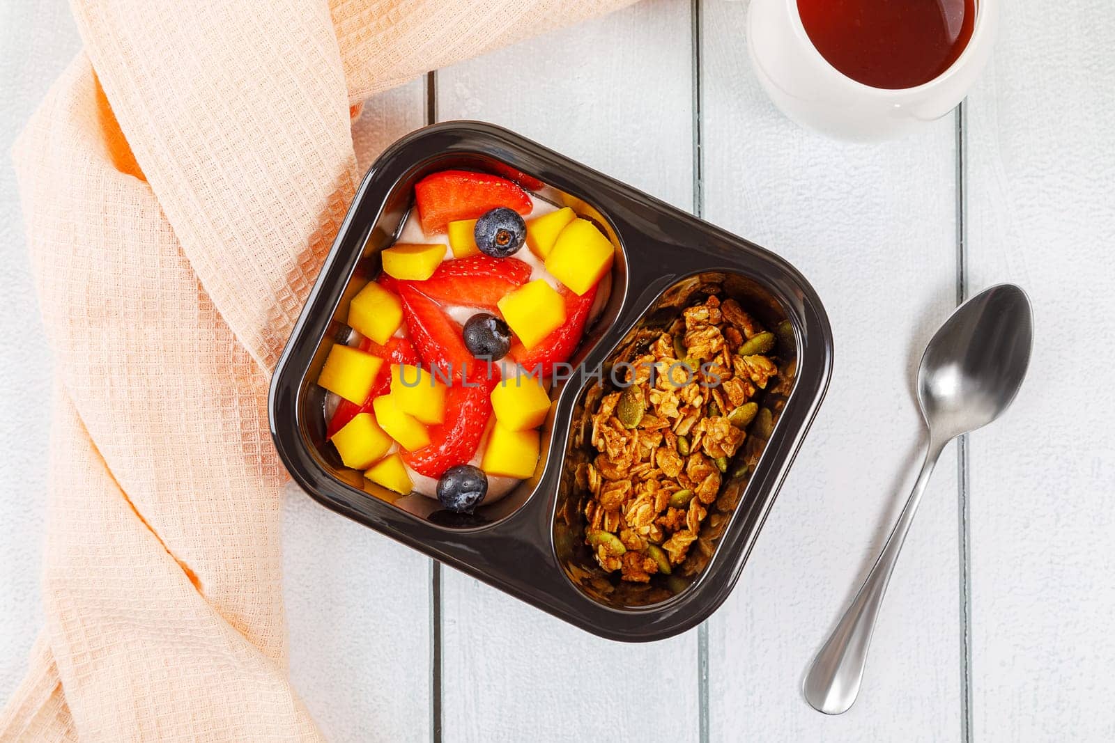 Dessert of cream, mango, strawberries and muesli on a wooden background. High quality photo