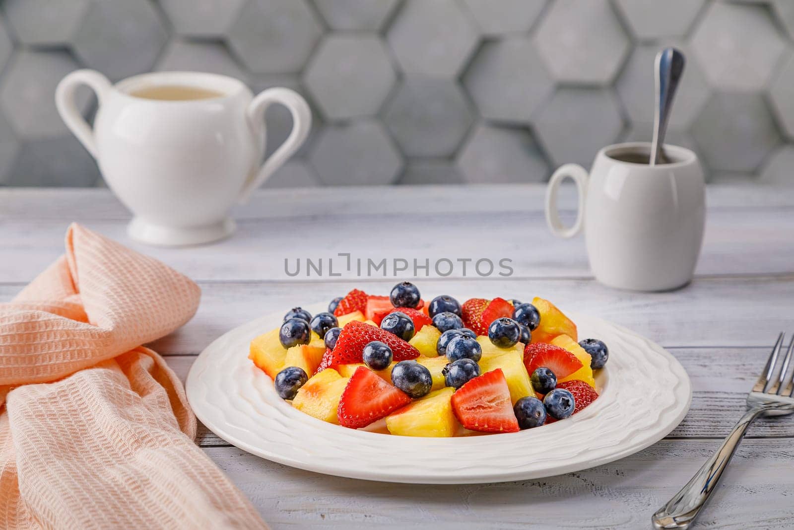 Fruit salad with pineapple, strawberries and blueberries on a white plate. High quality photo