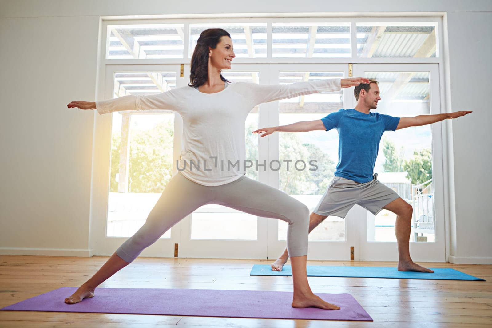 Practicing yoga together. Full length shot of a mature couple practicing yoga in their home