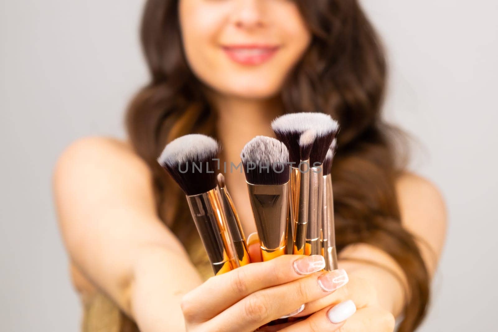Professional makeup brushes in woman hands on the grey background by vladimka