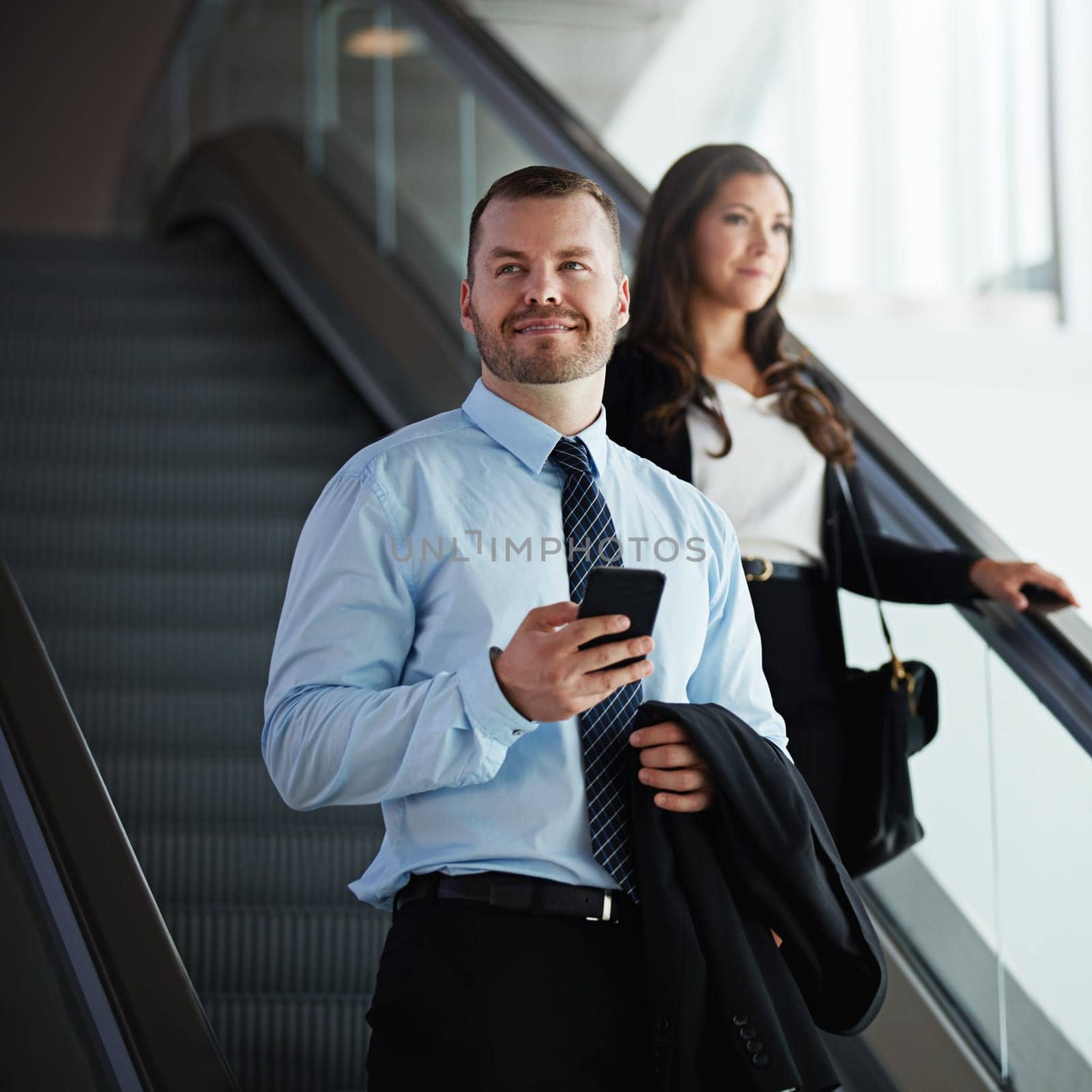 Pros in business travel. a businessman and businesswoman traveling down an escalator in an airport