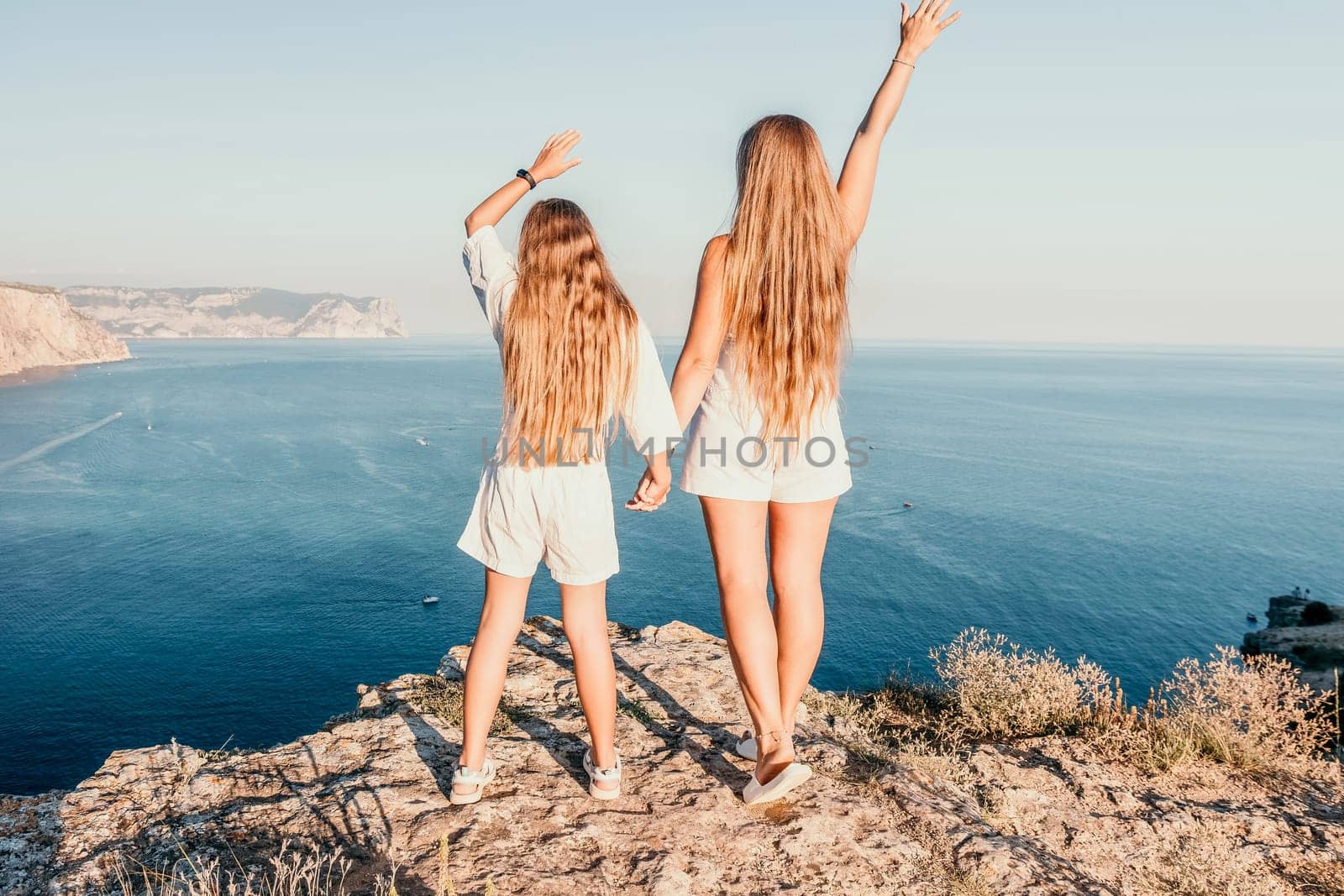 Close up portrait of mom and her teenage daughter hugging and smiling together over sunset sea view. Beautiful woman relaxing with her child.