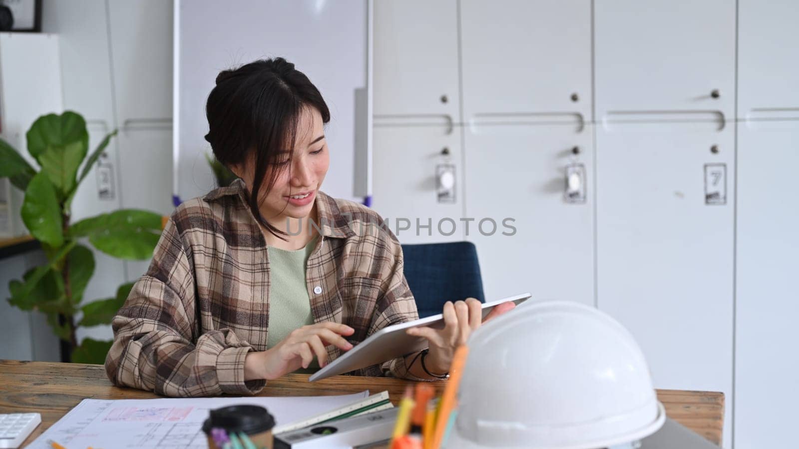 Female construction site engineer working with digital tablet in modern office.