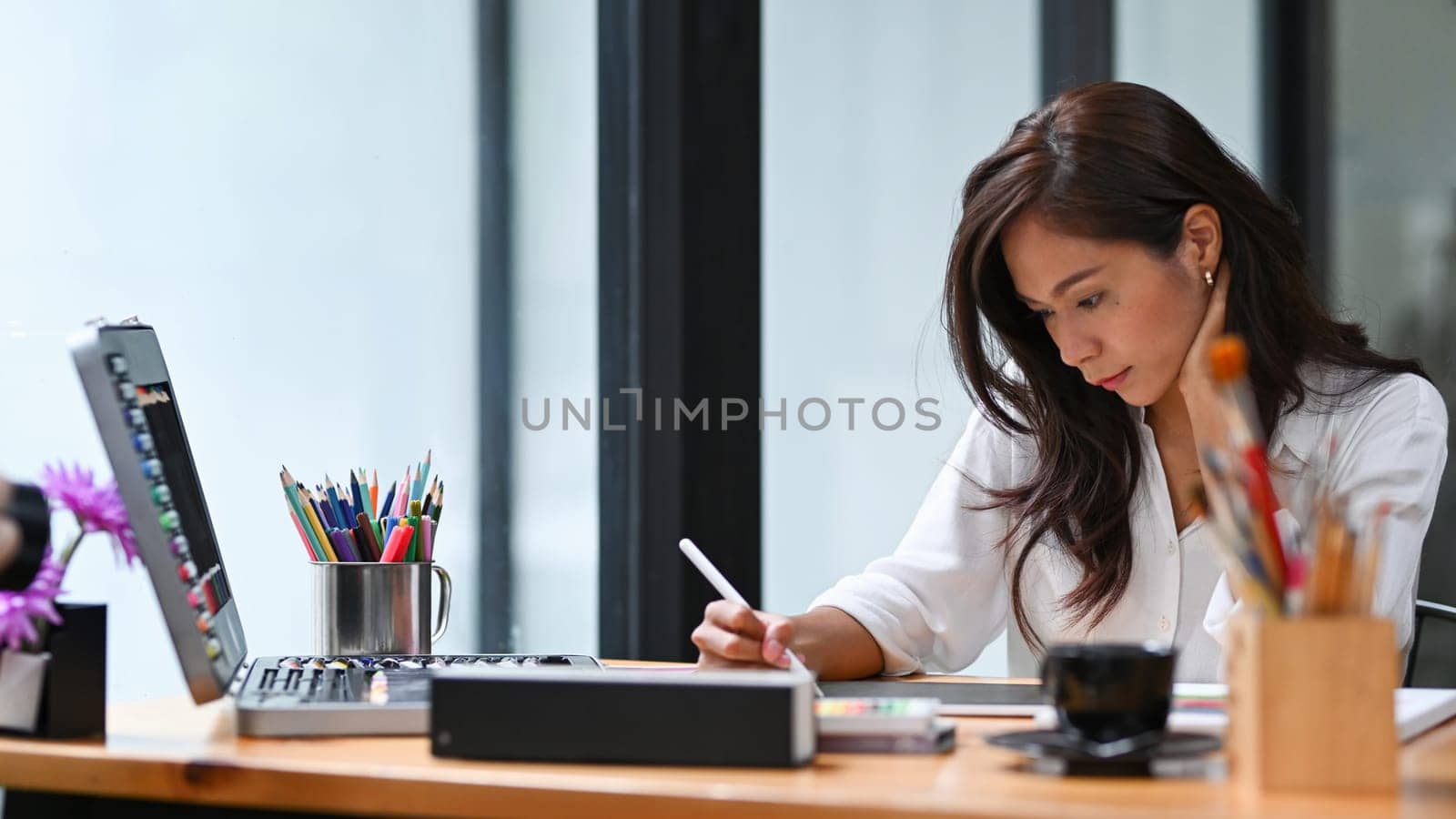 Beautiful creative woman working on new project with digital tablet in modern workplace.