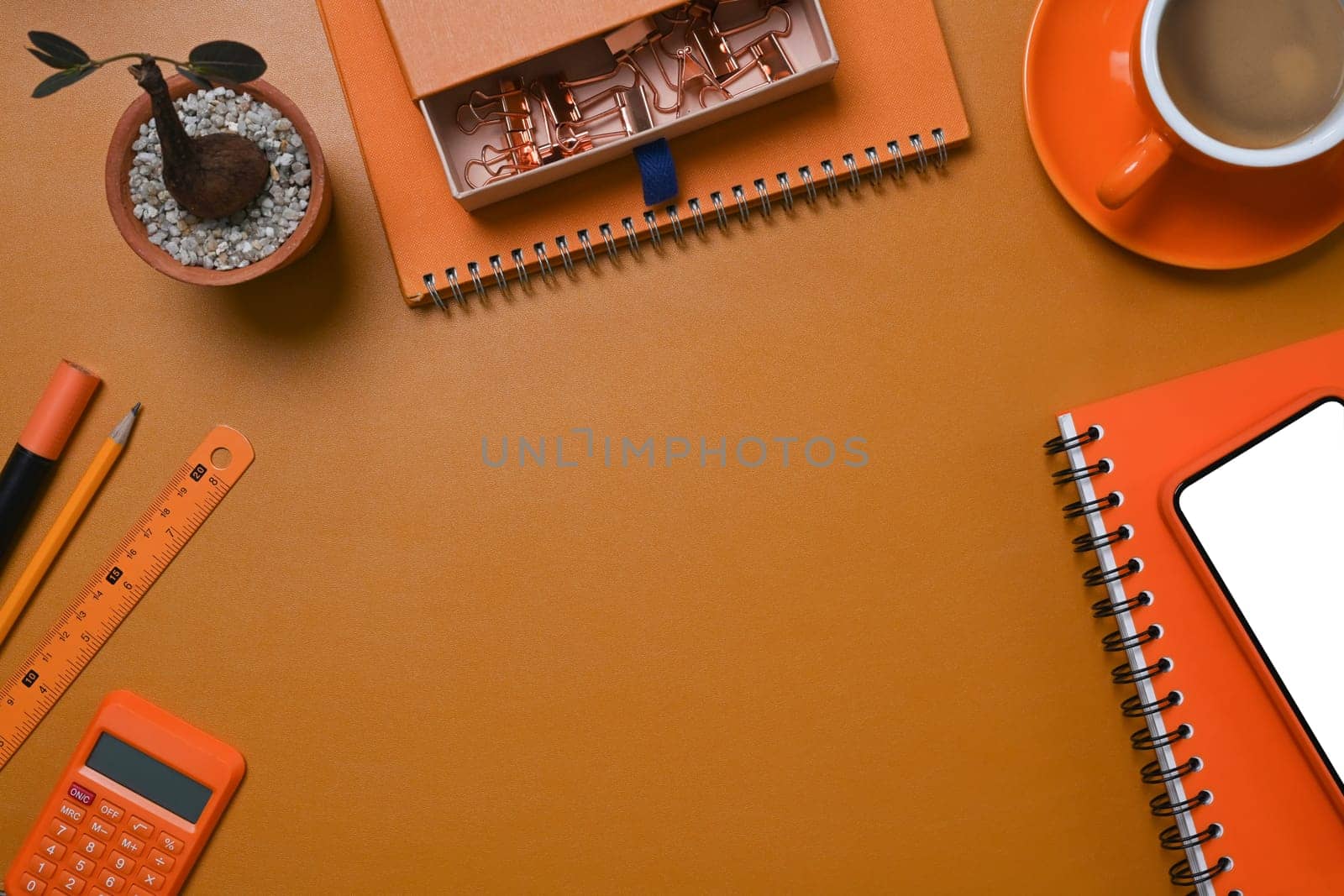 Stylish workspace with mobile phone, coffee cup and stationery on brown leather.