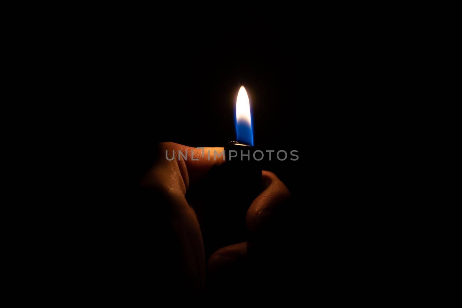 Burning lighter in hand in the dark close up