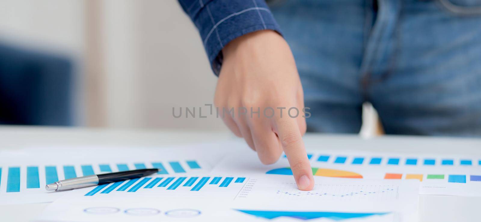 Hand of young business man pointing document data graph and chart paper, marketing and investment, report of statistics profit for financial, economic and growth of finance, management and planning. by nnudoo