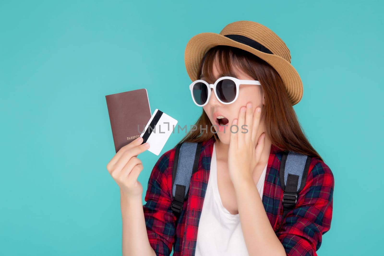 Beautiful young asian woman excited and surprise with showing credit card and passport to travel summer trip isolated on blue background, girl expression shocked journey in vacation.