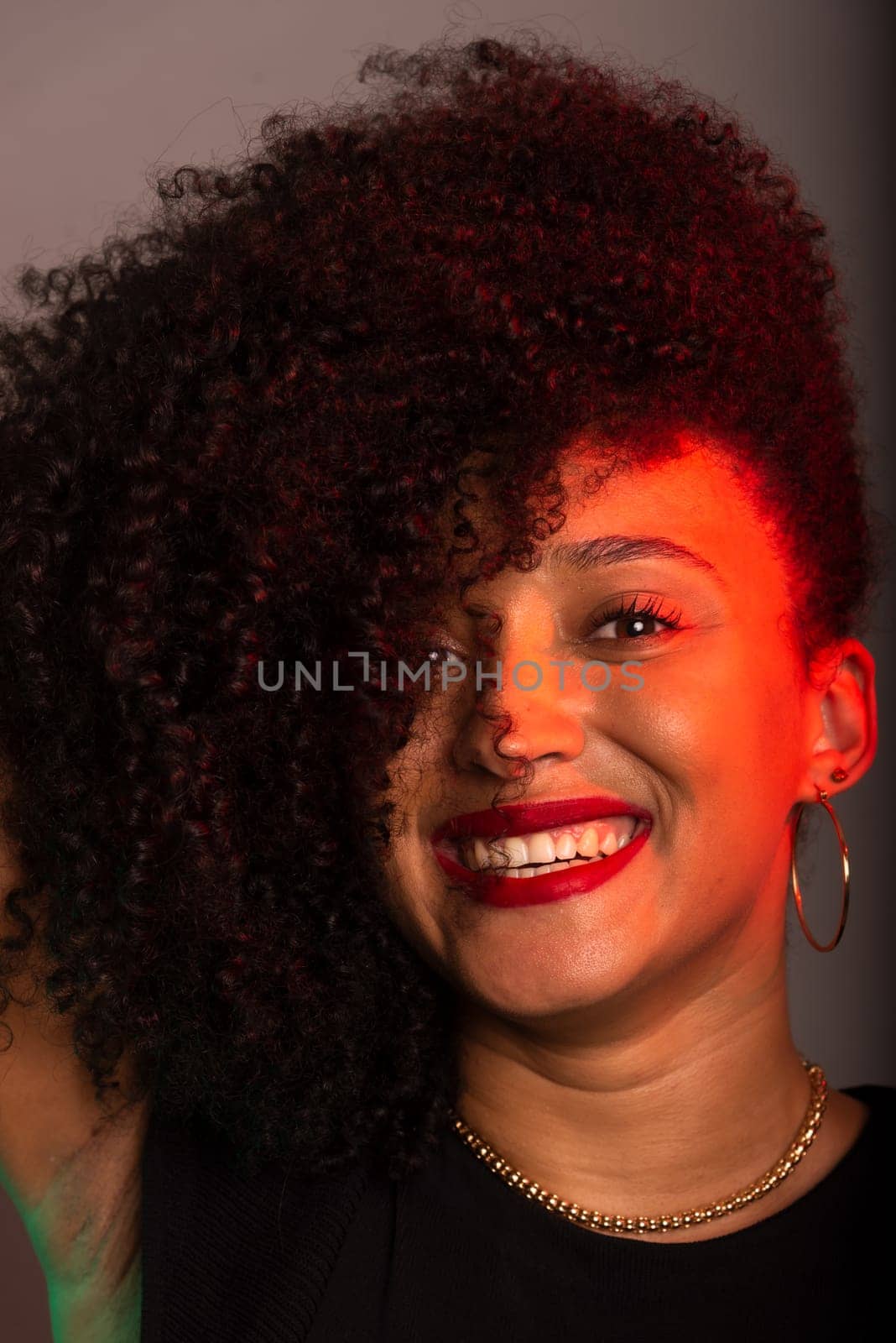 Vertical close-up portrait of beautiful young woman with hair to her face. Studio portrait.