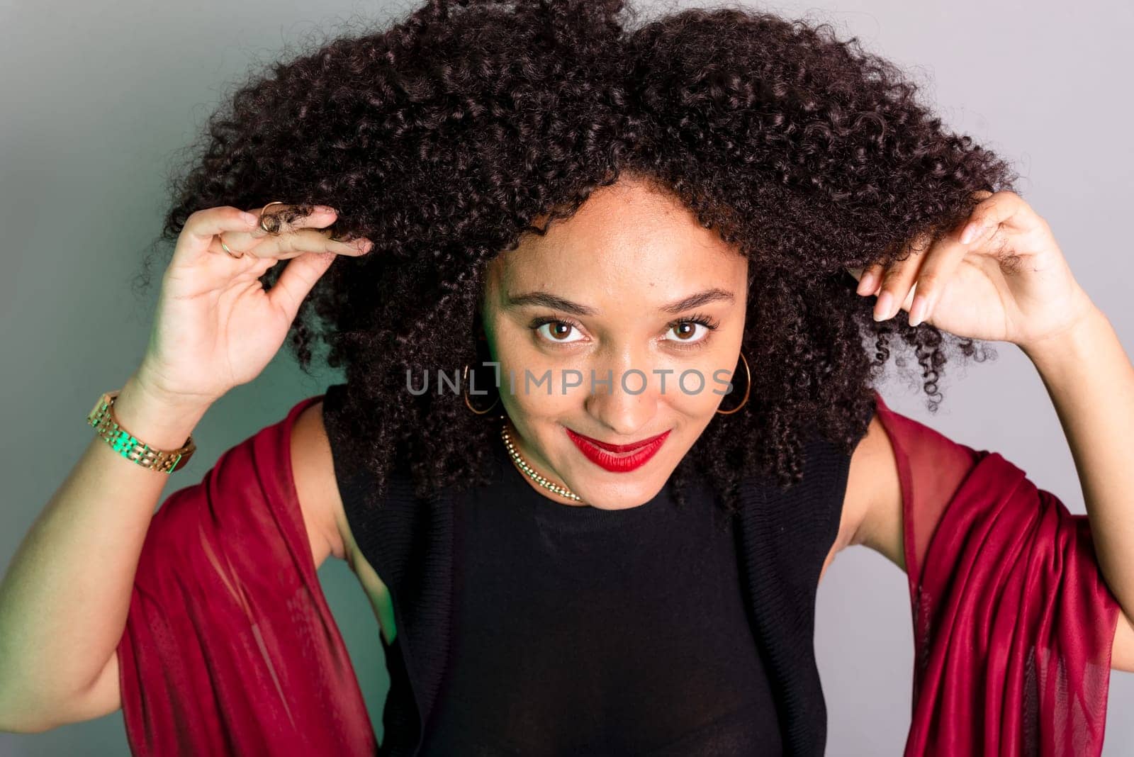 Beautiful young woman touching her hair with a red cloth. studio portrait