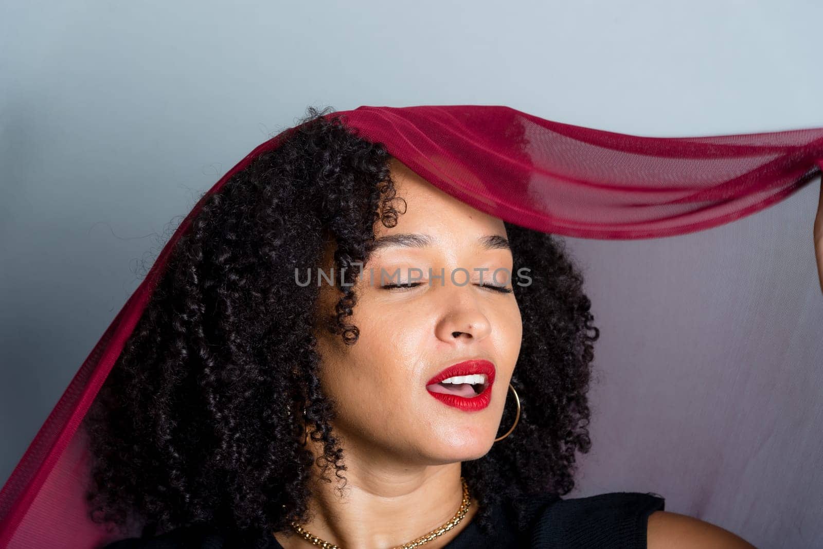 Beautiful young woman with red cloth suspended around her body. studio portrait