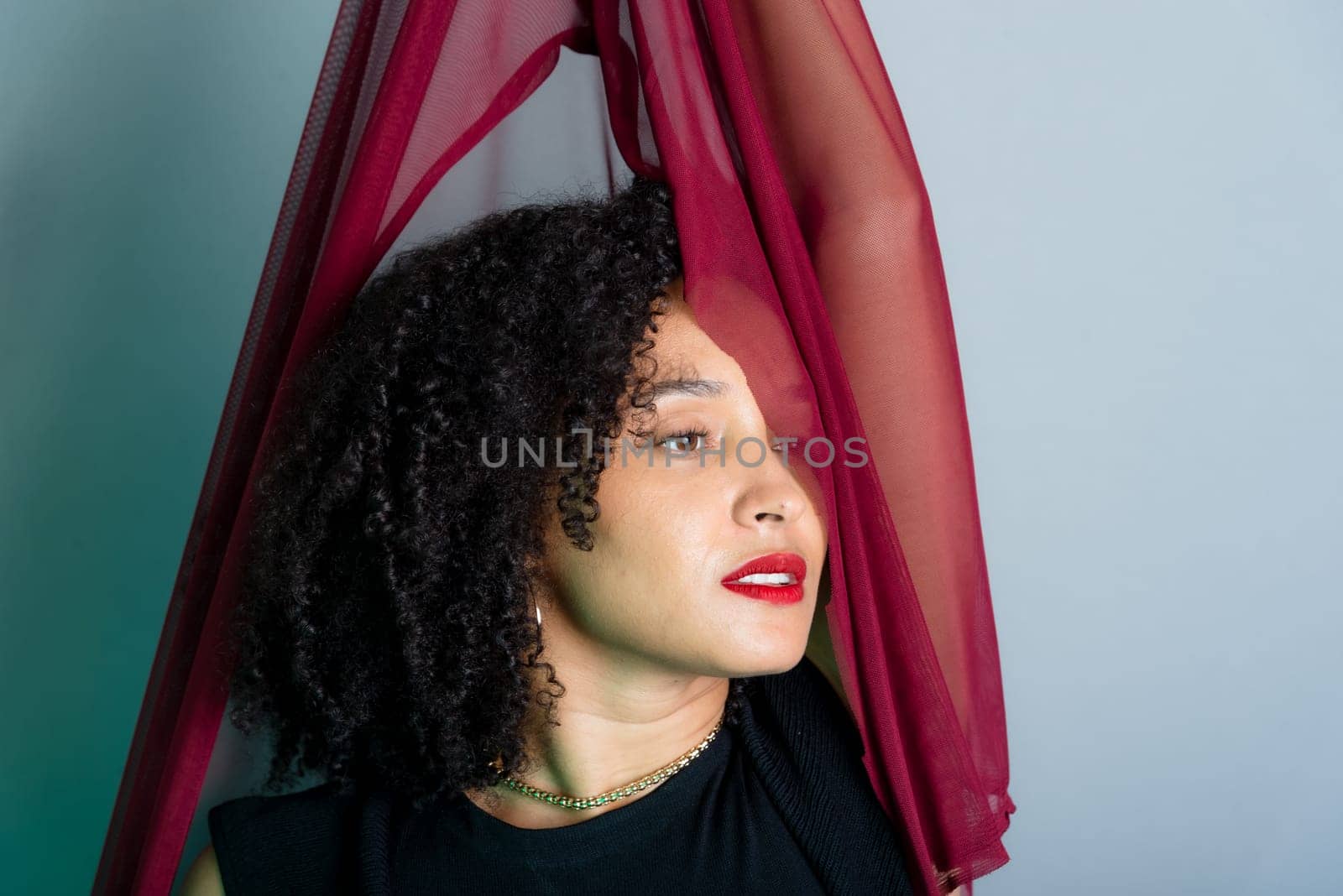 Beautiful young woman with red cloth suspended around her body. studio portrait