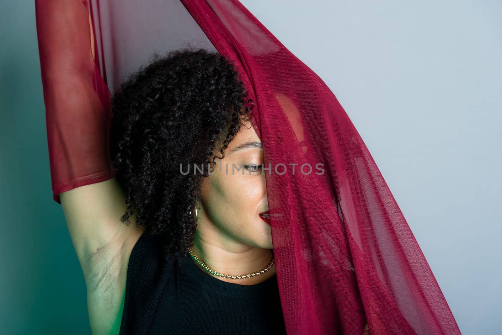 Beautiful young woman with red cloth suspended around her body. studio portrait